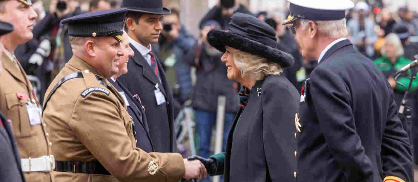 The Queen smiling as she shakes hands with someone from the military