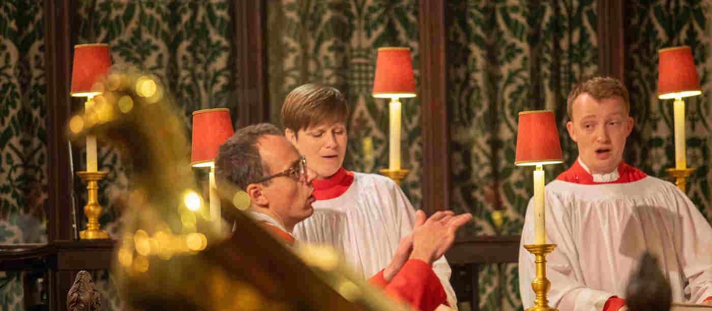 Photograph of members of St Margaret's Consort singing with the Director Music in the choir stalls of St Margaret's Church, Westminster Abbey