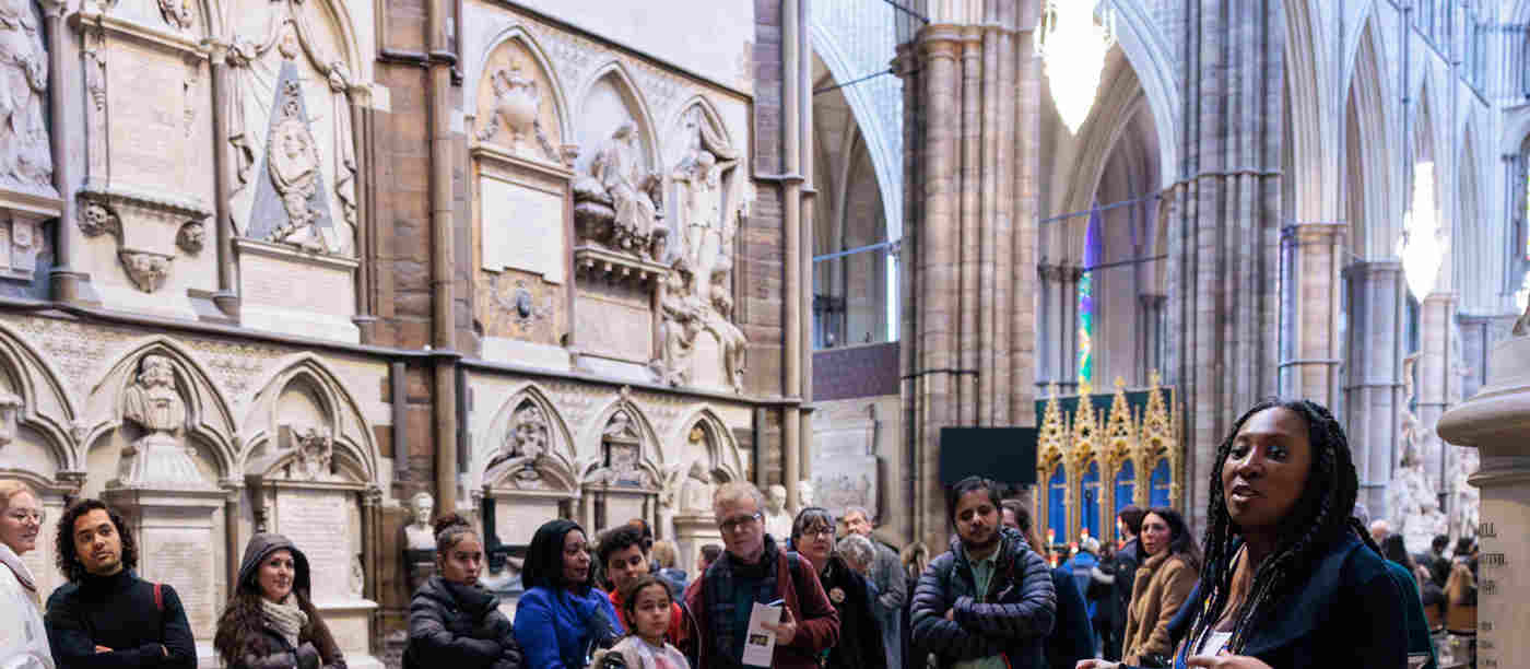 Photograph of members of the general public listening to a tour guide within Poets' Corner of Westminster Abbey