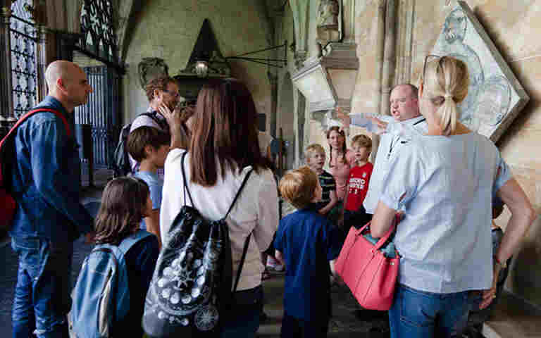 Photograph of the backs of young people and adults listening to a facilitator, representing home educated groups at Westminster Abbey