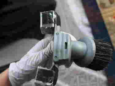 Close-up photograph of conservation cleaning tool being held by a hand wearing a white glove