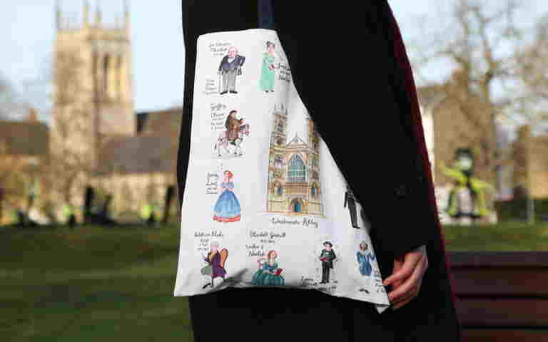 Person holding a tote bag featuring drawings of People of Westminster Abbey