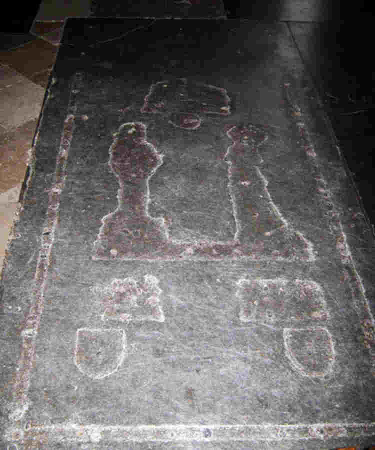 A grave stone with indents of lost brass decoration