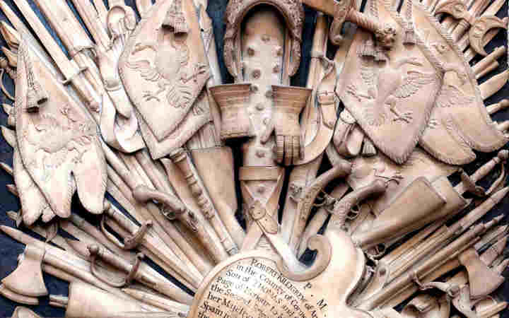 Close-up photograph of a memorial to the Killigrew family within Westminster Abbey, a stone tablet showing weapons