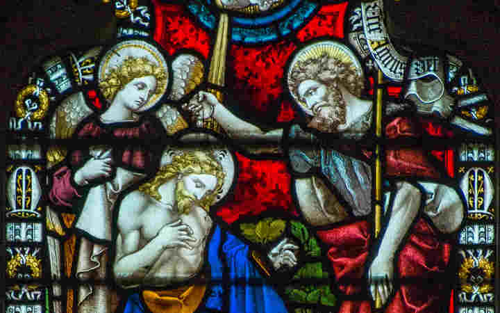 Photograph of Jesus being baptised in a stained-glass window in Westminster Abbey, representing a KS4 lesson about baptisms