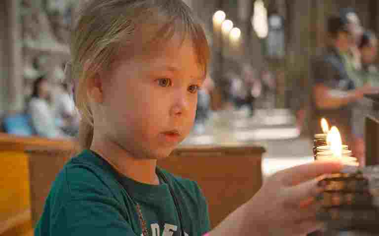 Photograph of child in Westminster Abbey lighting a candle