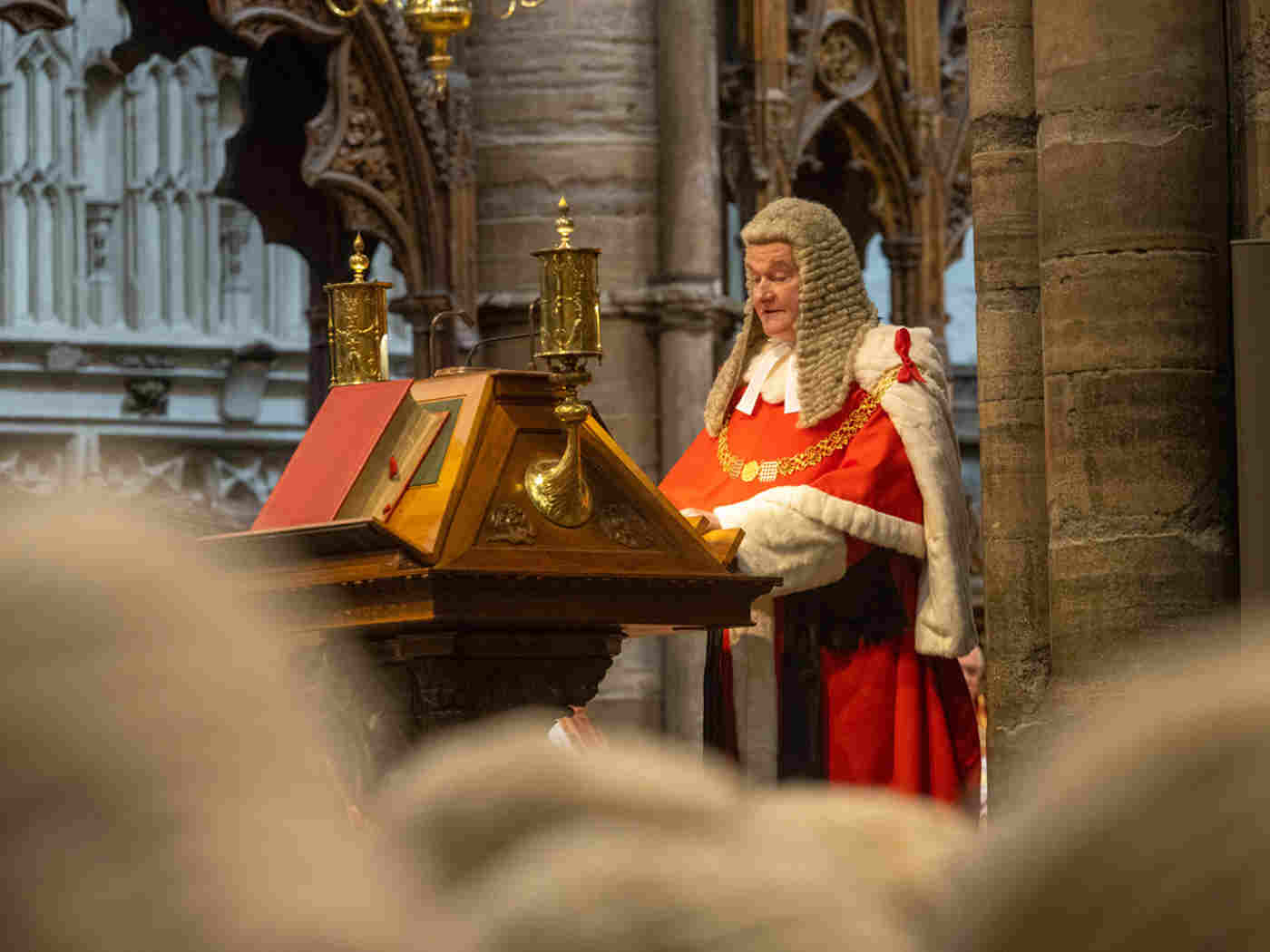 Lord Chief Justice of England and Wales wearing a red robe and legal wig whilst reading from the lectern