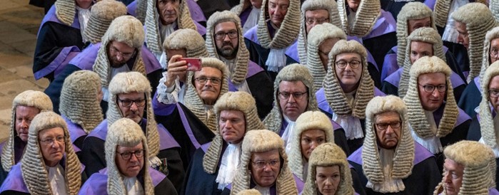 A group of judges, one is taking a selfie on his smartphone