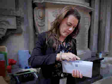 Photograph of woman standing within Westminster Abbey holding an envelope of information