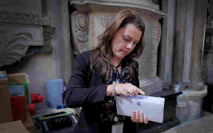 Photograph of woman standing within Westminster Abbey holding an envelope of information