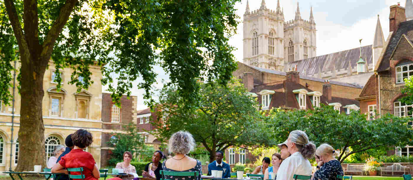 Photograph of visitors seated on chairs within College Garden, with the background of Westminster Abbey's West Towers
