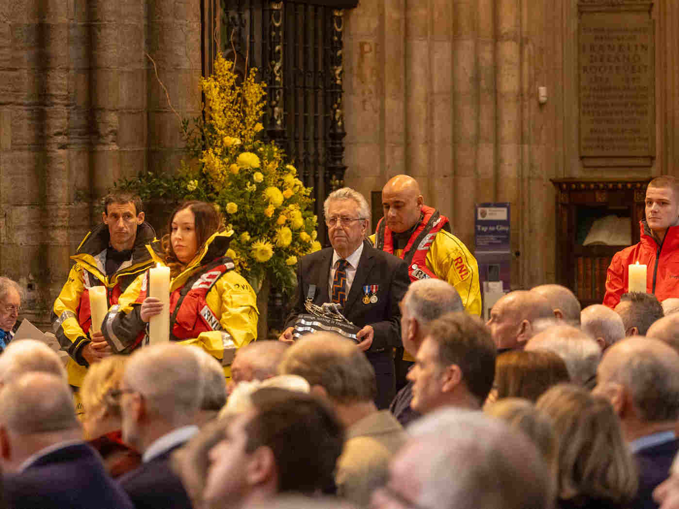 Members of the RNLI in waterproof yellow uniforms processing through the Abbey