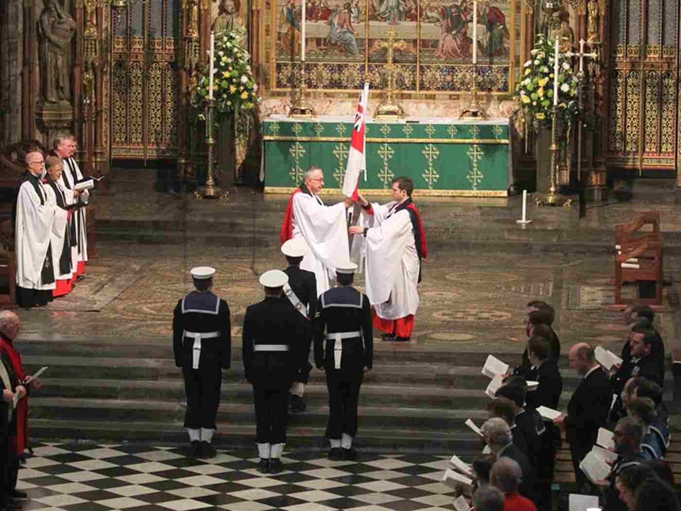 The Dean of Westminster receives a flag which has been brought to the altar by four sailors