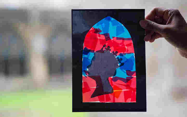Photograph of a hand holding a stained glass window craft using scraps of paper