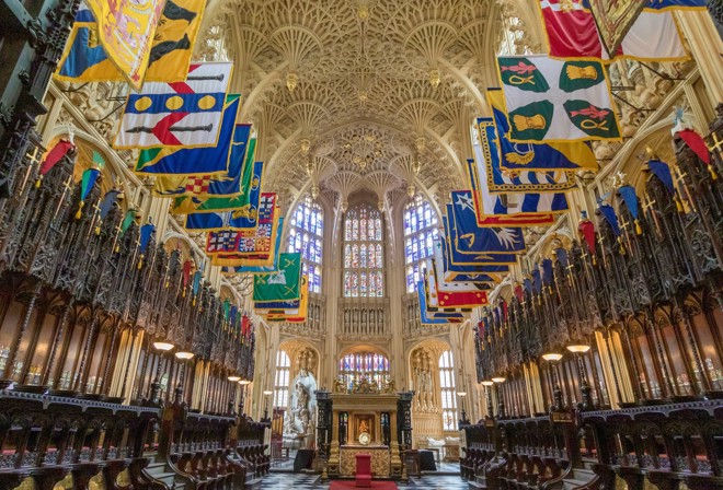 A photograph of the Henry VII chapel at Westminster Abbey, with its spectacular fan vaulted ceiling and colourful heraldic banners hanging on either side of the shot