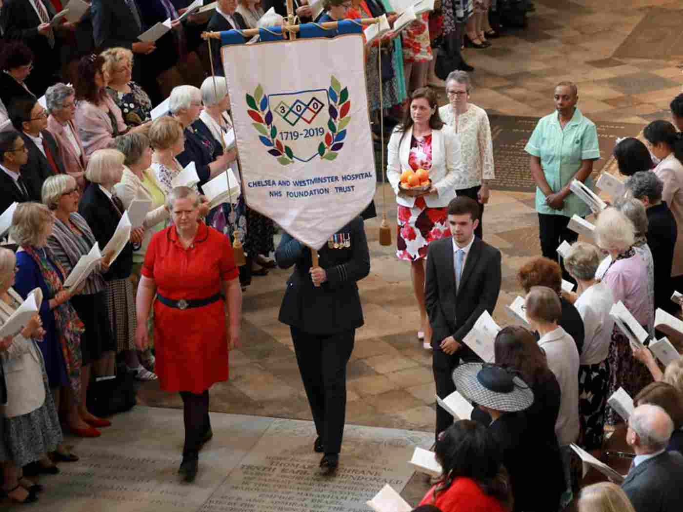 The Chelsea and Westminster Hospital NHS Foundation Trust banner and a bowl of oranges, remembering the Hospital's first in-patient, who was cured of scurvy, are processed