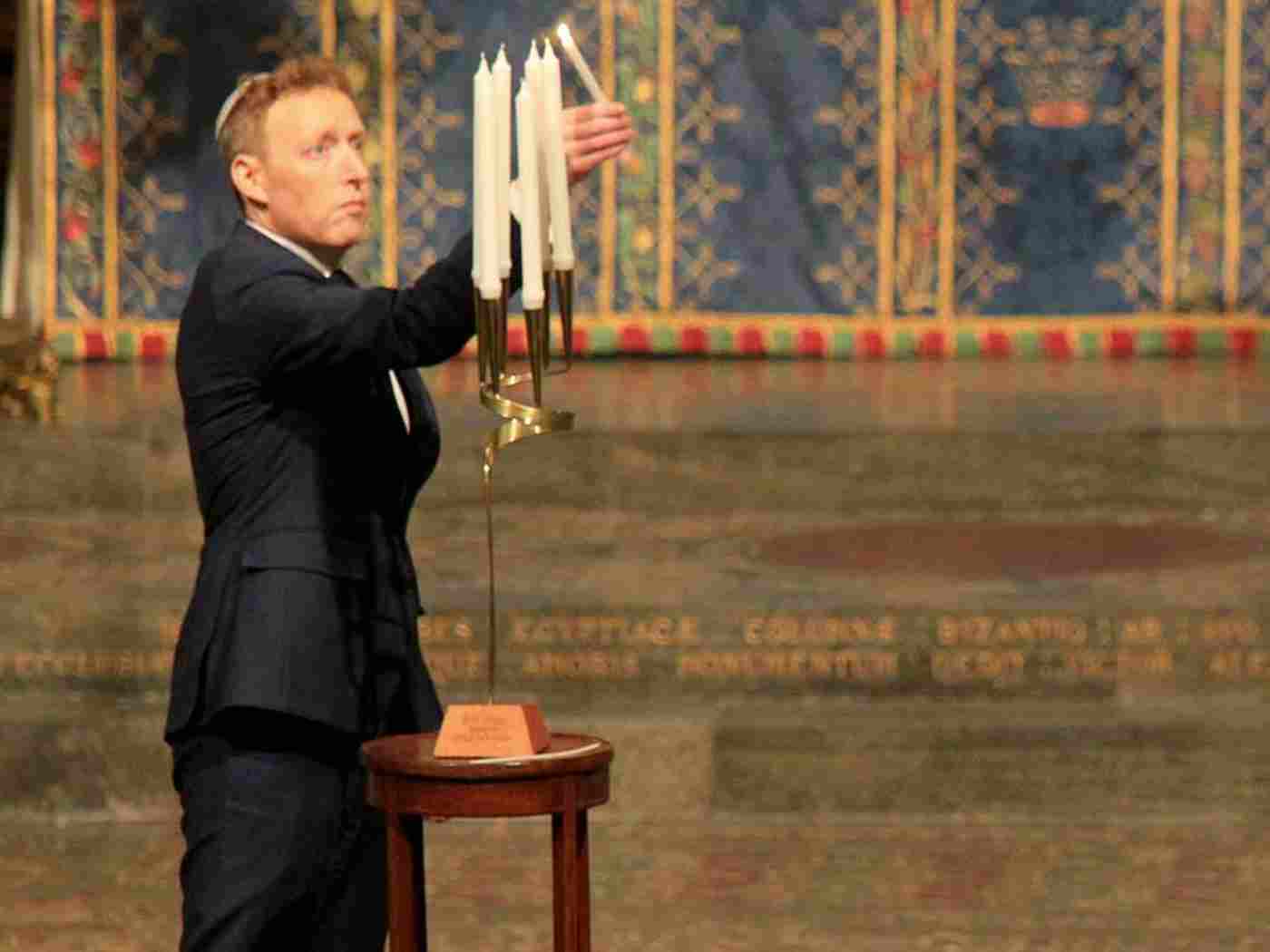 Michael Newman, Chief Executive, the Association of Jewish Refugees, lights a memorial candle