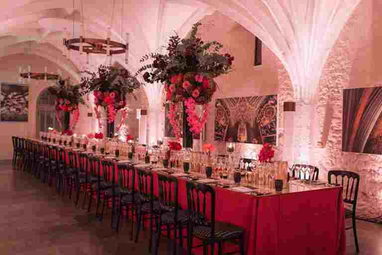 Setting for a formal dinner in the Cellarium, Westminster Abbey, with red tablecloth and flowers