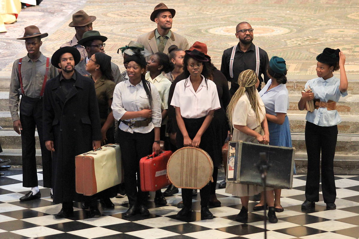 Actors dressed as people who have just arrived in England on HMT Windrush. They are all carrying suitcases