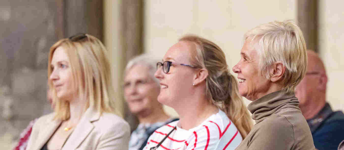 Photograph of people sitting and looking in one direction, listening to a talk at Westminster Abbey