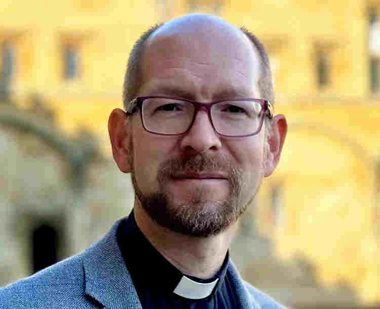 Photograph of Andrew Davison, the Regius Professor of Divinity at the University of Oxford, a white man wearing glasses and a suit