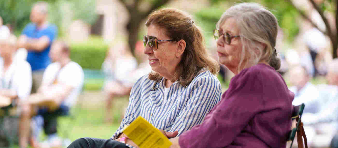 Photograph of two members of the public sitting and looking within College Garden in Westminster Abbey