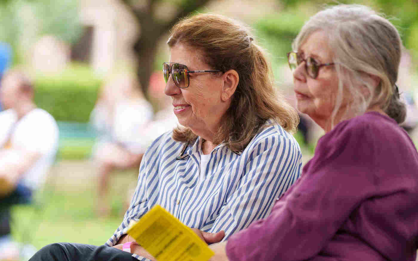 Photograph of two members of the public sitting and looking within College Garden in Westminster Abbey