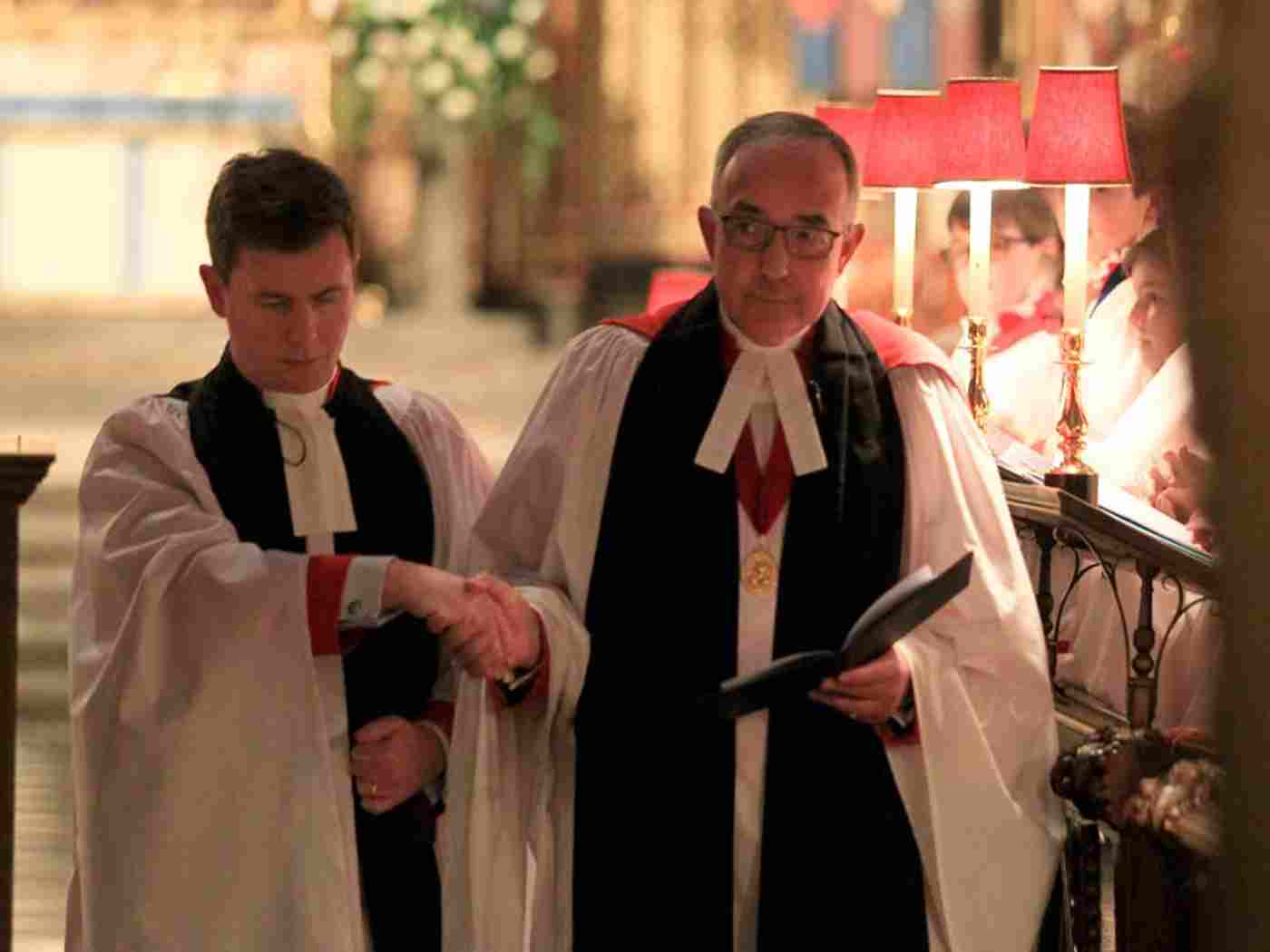 Canon Hawkey is led to his stall in the Quire by the Dean