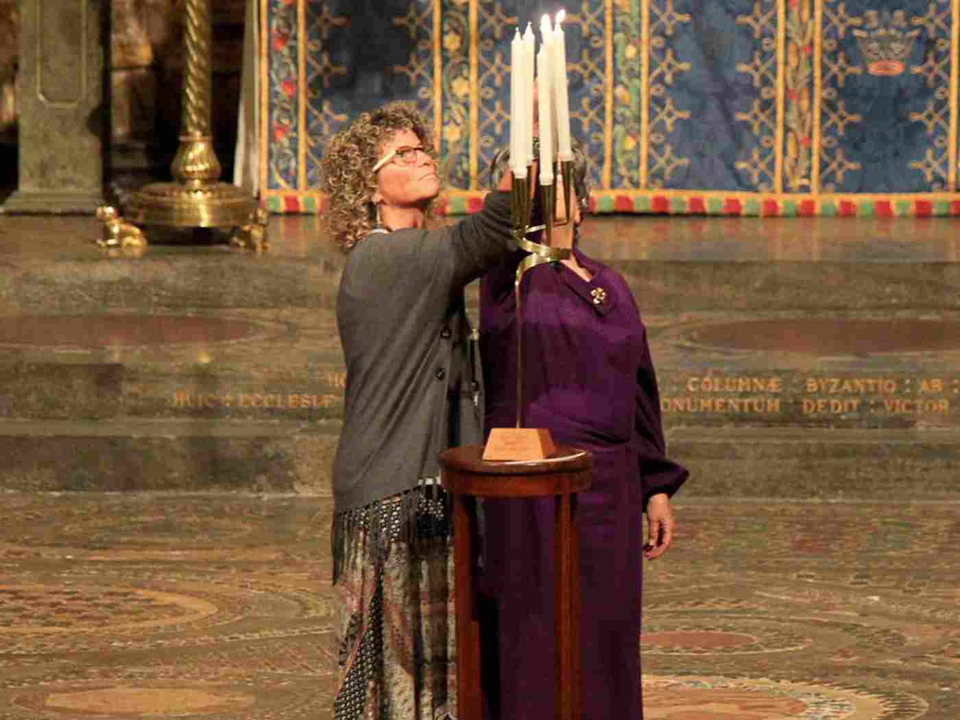 Lilian Levy, survivor, with her daughter Hilary Solomon, lights a memorial candle